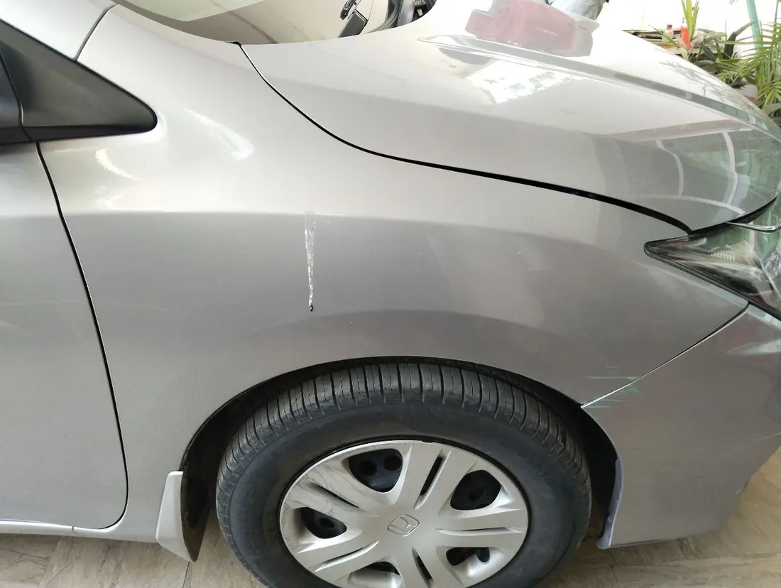 Scratch running down a front fender of a silver sedan found during pre-purchase inspection in Lahore