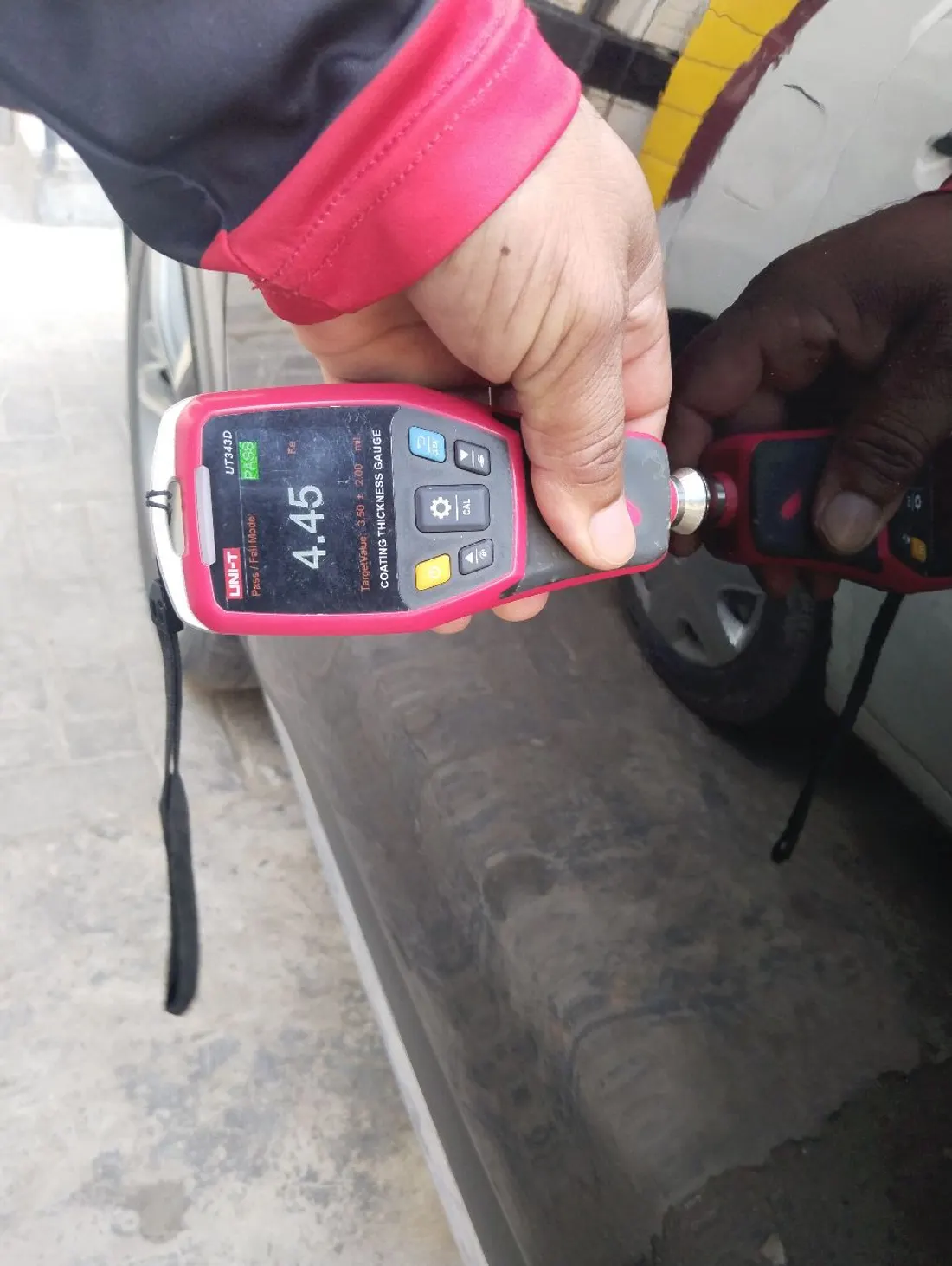 Paint thickness gauge reading 4.45 mils PASS on an original factory panel during a CarOK inspection in Lahore